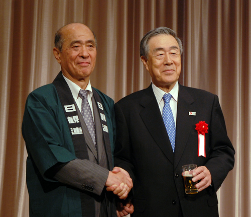 日観連の懇親会で握手する近兼会長（左）と佐藤会長