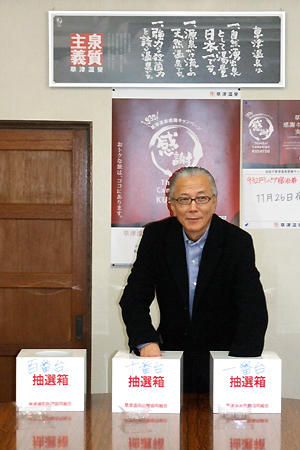 抽選箱に手を入れ選ぶ市川旅組理事長