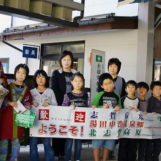 旅行客の到着を待つ女将と地元の小学生