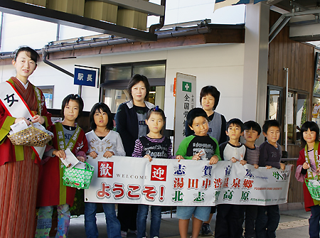 旅行客の到着を待つ女将と地元の小学生