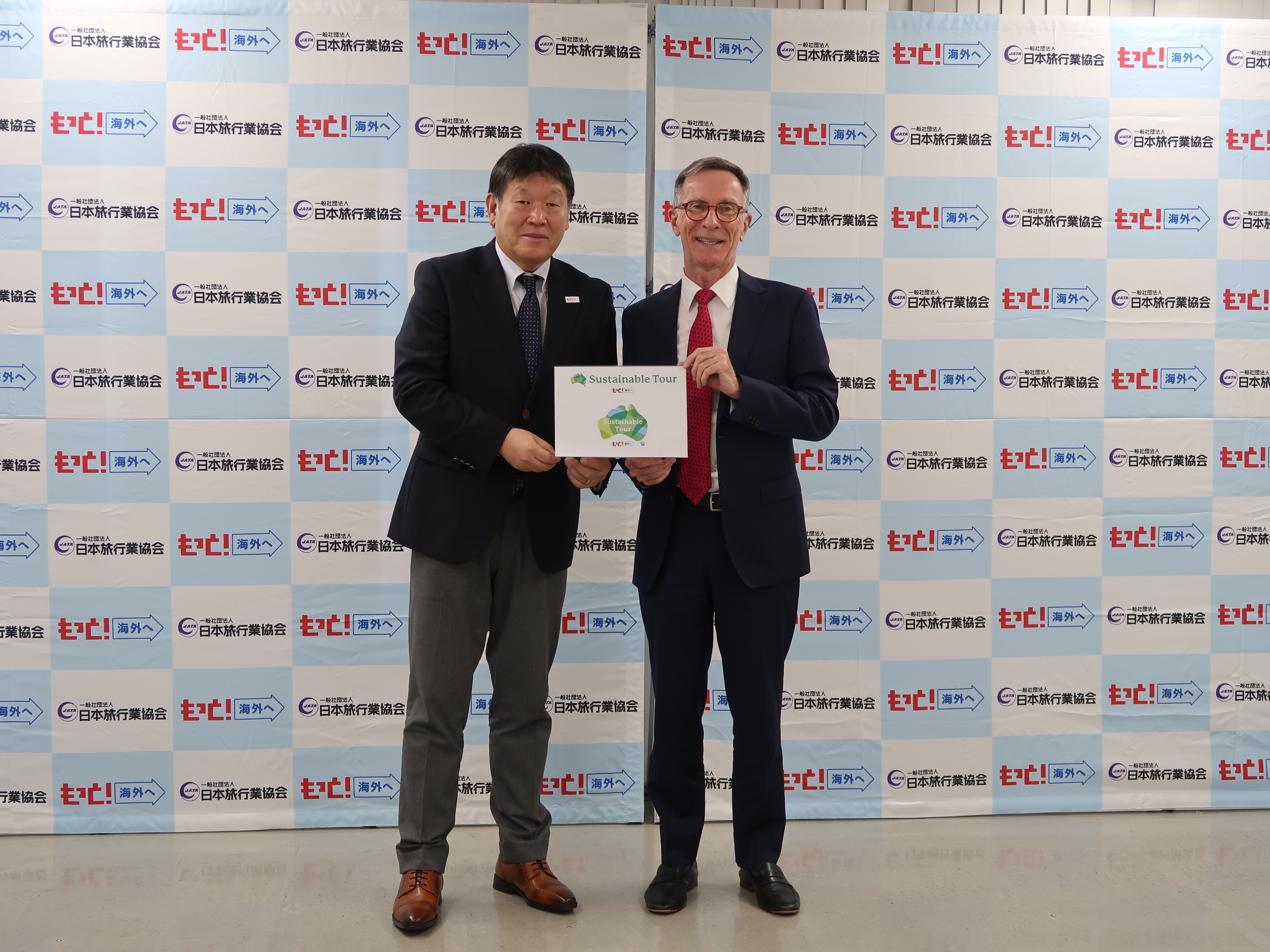 ロゴマークを披露する秋山部会長（左）と、豪州政府観光局のベインズ局長